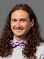 A portrait of a man with brown hair wearing a bow tie.